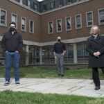 Three people (including Mark Willcock Left) in the courtyard in front of St. Peter's Evangelical Lutheran Church, Kitchener