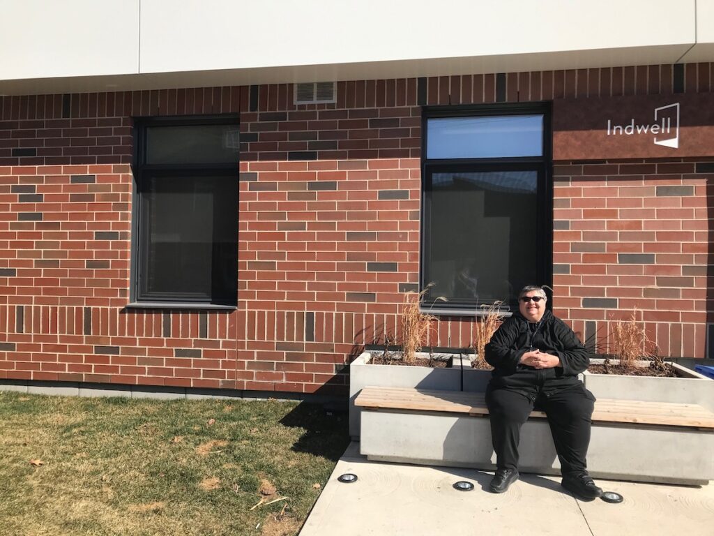 Doroca, tenant sitting in front of her building, North End Landing, Hamilton