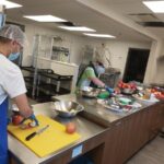 Tenants work with staff Lorna Murray at a counter in Blossom Park kitchen - creating preserves for a social enterprise, Gather - 2020