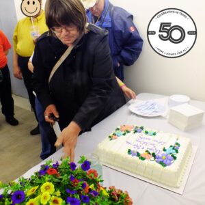 A long-time tenant cuts and serves cake at the Caroline Apartments Post-Renovation Celebration, 2014